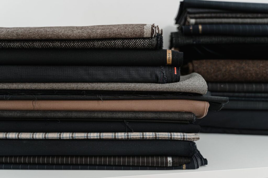 pexels photo 6764917 A neatly arranged pile of diverse fabrics, ideal for a fashion designer or tailor's workshop.